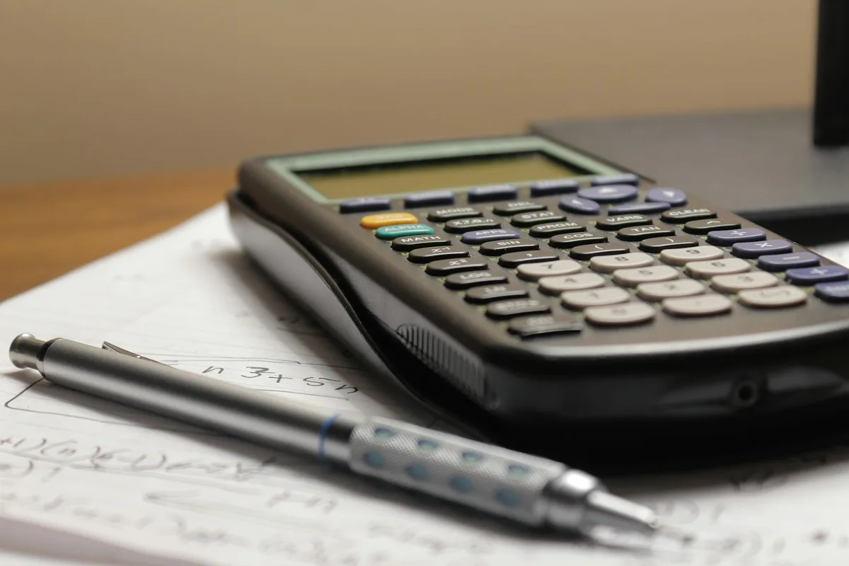 A calculator and a pen resting on a sheet of paper.